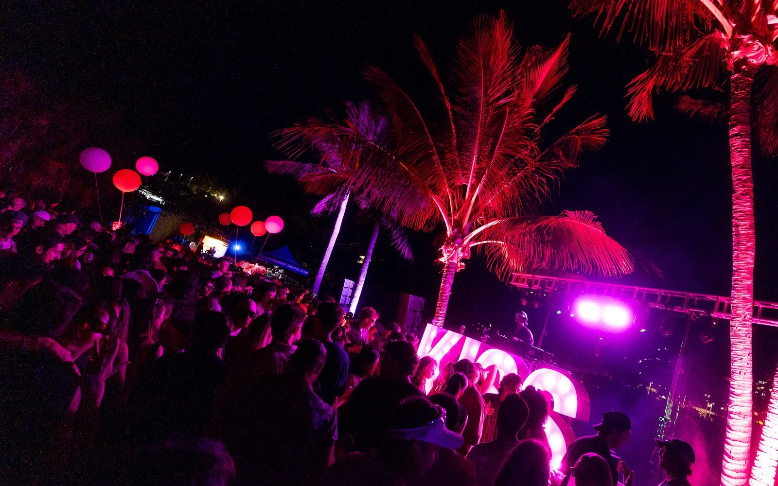 WeKiss stage under the palms with the club sign lit up